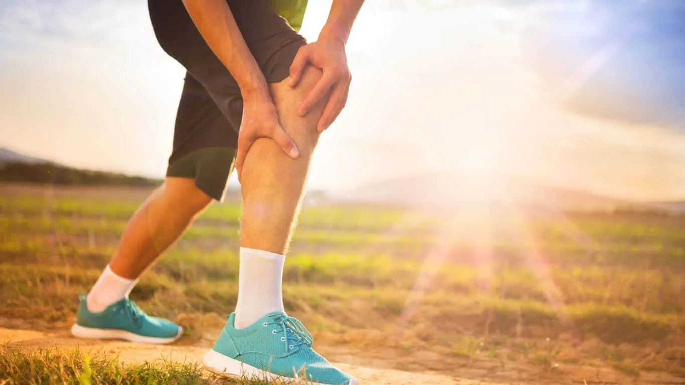 Hombre sentado en el suelo con dolor de rodilla